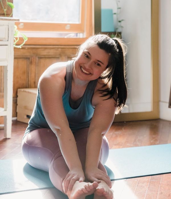 Smiling person stretching in a bright, sunlit room.