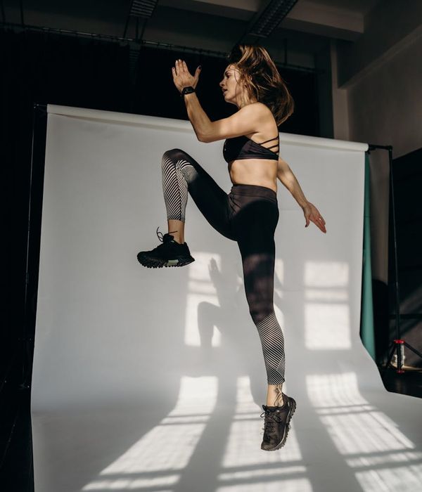 Woman in activewear performing a light cardio exercise indoors.
